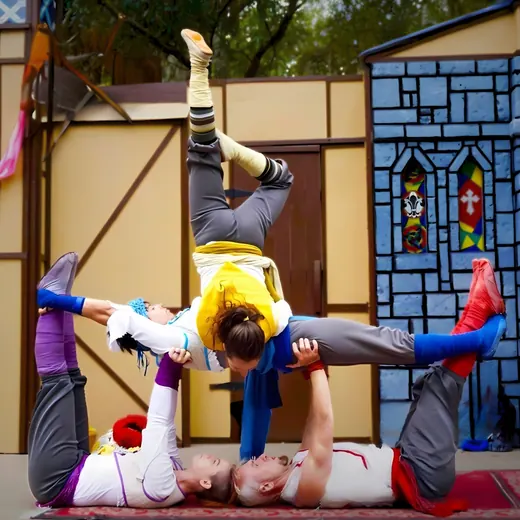 Acrobellum acrobats balance in a stacked lift in front of a painted castle set