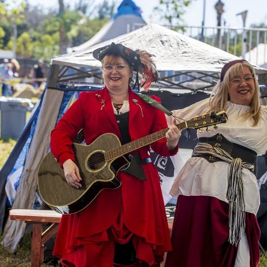 The Captain's First Mate, the Crimson Kitty, plays guitar in red beside a fellow singer