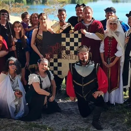 The Royal Chessmen stage combat troupe gathered in costume around their chequered banner