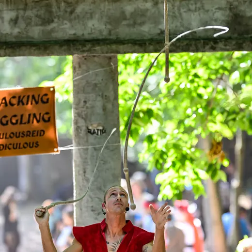 Reid Conklin cracks a bullwhip high above his head under the trees